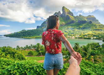 Follow me couple influencers tourists walking on Bora Bora island, Tahiti. Woman leading man off the beaten path exploring nature hiking trail in French Polynesia. Mt Otemanu wanderlust summer travel.