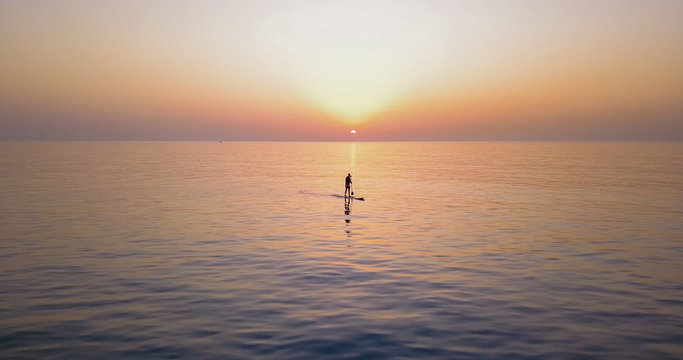 SUP Surfing on amazing sea sunset.  Image of Stand Up Paddle Board Man Silhouette on Amazing Sunset over Sea. Standup Paddle Boarding.