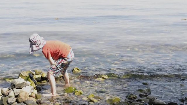 Boy playing on a beach with stones