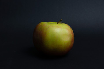 juicy red-green apple on a black background