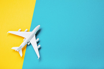 A small white toy plane on a paper background with a copy of space. Concept of travel and air travel, top view