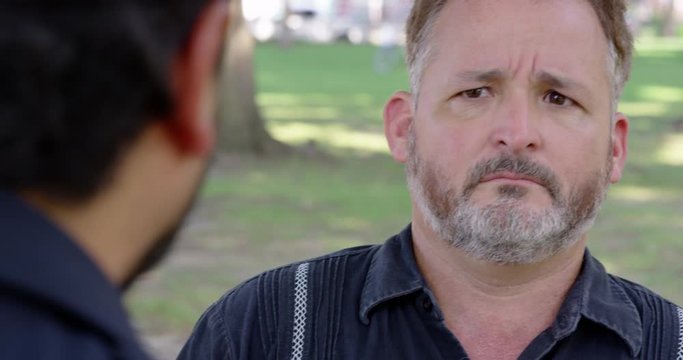 Closeup - A man is being berated by another man while outside at a park - shot on RED