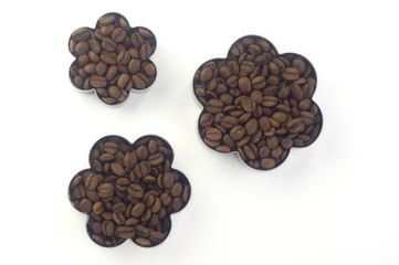  three containers of different sizes in the shape of a flower filled with coffee beans and standing in a row next to each other on a white background. Flat lay