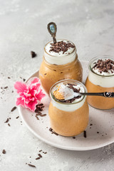 Chocolate mousse with whipped cream and pieces of chocolate in portion glasses, light grey background. Copy space.