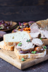 Roast beef sandwich with vegetables, champion and herbs on wooden cutting board, rustic style.
