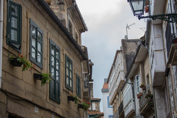 Fototapeta na wymiar Santiago de Compostela landmark. Buildings at old medieval street. Camino de Santiago concept. European architecture. Windows, outdoor flowers and lantern at narrow street. Pilgrimage centre.