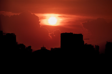 Naklejka premium Red evil and menacing looking sky with the sun behind the clouds over skyscrapers and a the city of Hanoi, Vietnam
