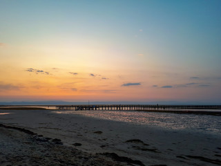 Obraz premium Colorful sunrise sky with pier in the sea during low tide at the beach of Grado