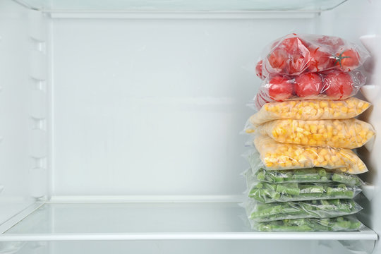 Plastic bags with different frozen vegetables in refrigerator