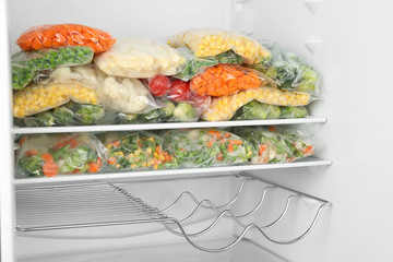 Plastic bags with different frozen vegetables in refrigerator