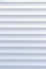 Roller shutter texture. Background with metal stripes in white. Iron roller shutters of white color. Abstract background for wallpaper in the form of straight lines.