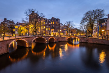 Fototapeta premium Night view of Amterdam cityscape with canal, bridge and medieval houses in the evening twilight illuminated. Amsterdam, Netherlands