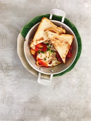 The menu consists of fried egg with chopped pork, tomatoes, sausages,vegetables and breads in the pan on the cement background, usually serving for breakfast.