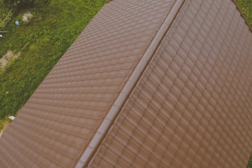 Brown metal tile on the roof of the house. Corrugated metal roof