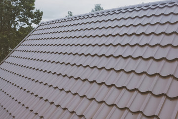 Brown metal tile on the roof of the house. Corrugated metal roof