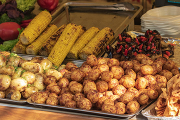 Culinary buffet with the presentation of healthy food - mushrooms, potatoes, sausages, peppers, spices, grilled vegetables. Food market, festival, event. The kitchen is outdoors. Street fair stand.