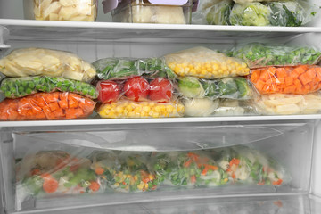 Plastic bags with different frozen vegetables in refrigerator