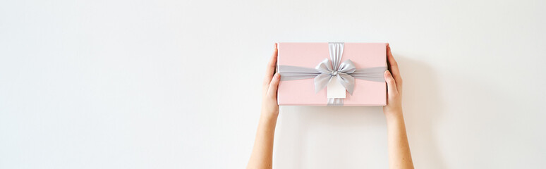 A girl holds a gift box on a white background. Banner, copy space