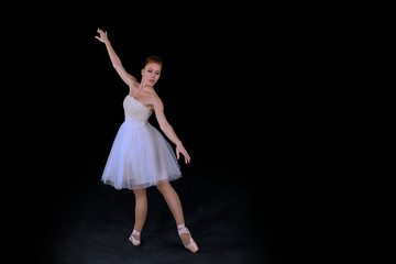 Fototapeta premium the ballerina in pointes and a dress dances on a black background