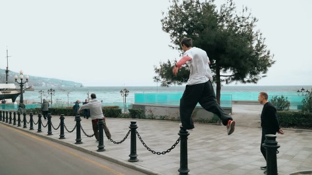 Guys jump on iron fences in the city. The guy is training parkour. Jumps on the railing on a cold autumn day. Does a backflip. Cleverly jumping. Parkour.