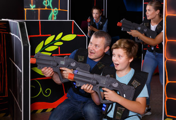 Happy boy and his father aiming laser guns