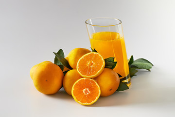 Tangerines with green leaves, a glass of juice