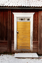 an old worn yellow wooden door to an equally old house when the first snow has arrived