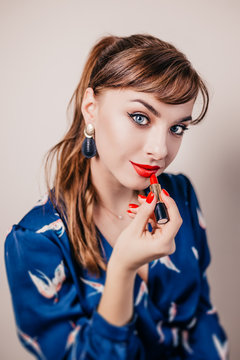 Girl paints her lips with bright red lipstick - cosmetics - evening makeup in retro style