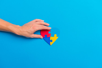 Hand Holding Colorful Heart On Blue Background. World Autism Awareness Day Concept