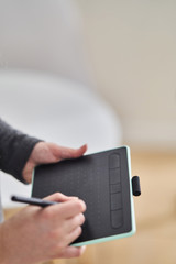 A young girl draws on a graphics tablet. Freelancer works in a cafe