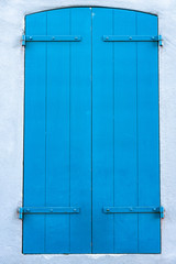 Window of house closed with blue shutters outside the house.