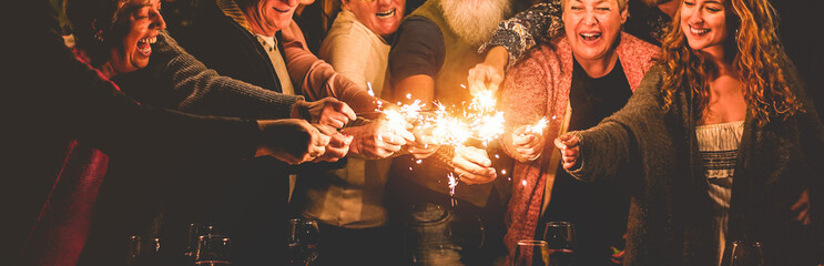 Happy family celebrating christmas holidays and new year with sparkler fireworks - Different age of people having fun together in patio party - Celebration and vacation concept - Focus on center hands