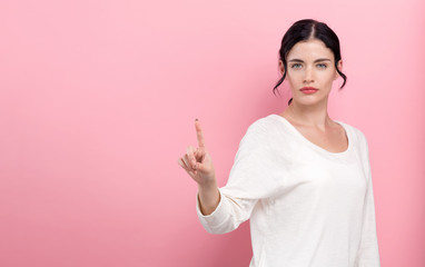 Obraz premium Young woman pointing at something on a pink background