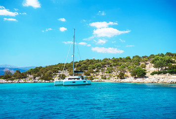 Sailing yacht catamaran boat with white sails on turquoise waters of sea.