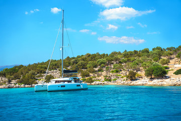 Sailing yacht catamaran boat with white sails on turquoise waters of sea.