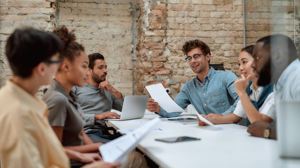 Together we can do so much. Group of young business people discussing something while working...