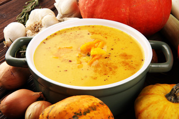 Roasted pumpkin and carrot soup with cream and pumpkin seeds on rustic background.
