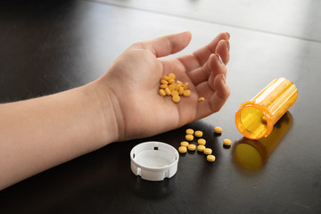 Photo reflecting the perscrition drug crisis. A young person with a container of spilled pills.