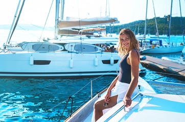 Happy young woman feels fun on the luxury sail boat yacht catamaran in turquoise sea in summer...