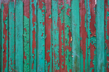 Old wooden fence.turquoise and red.Old peeling fence.Old paint on the fence discolored in places.