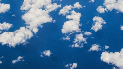 Little white clouds in the blue sky from the airplane window