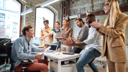 Surprise. Mixed race happy people celebrating a birthday of colleague in the modern office