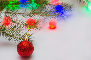 branch of new year tree with colorful toys and garlands with multi-colored light bulbs 