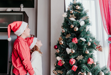 brother and sister decorating christmas tree at home. Family time. Christmas concept