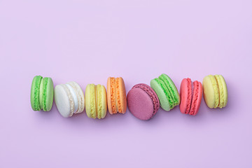 Top view of colorful macaron biscuits in a row on pastel color block background, flat lay