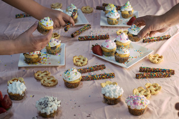 hands taking colorful desserts from a pink table