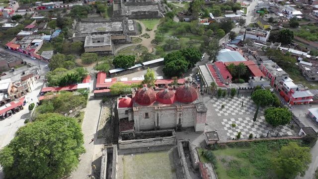 Beautiful Church San pablo villa de mitla with beautiful red rood and pyramid complex in Oaxaca Mexico. Aerial drone view. flying forward..