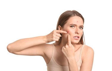 Portrait of young woman with acne problem squishing pimples on white background
