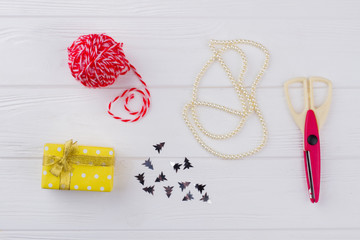 Christmas gift packaging composition. Present box, scissors and threads on white rustic wood. Making box for christmas or other holiday. Winter holidays diy background.