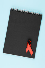 red aids ribbon on open notebook
